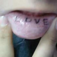 L'amour tatouage aux lettres noires et simples sur la lèvre