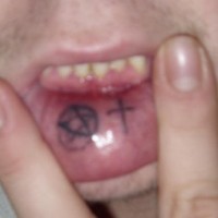 Lip tattoo, two black  signs, round circle and cross