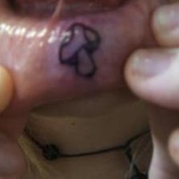 Tattoo mit kleinem Zeichen,das einem Pilz ähnlich ist,  an der Lippe