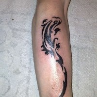 El tatuaje tribal de una lagartija de color negro en el brazo