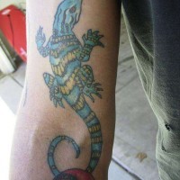 El tatuaje detallado de una lagartija de color azul en la mano o brazo