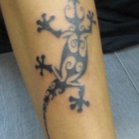 El tatuaje tribal de una lagartija de color negro en la pierna