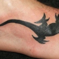 El tatuaje de una lagartija negra en el pie