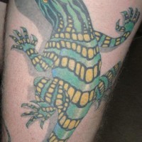 El tatuaje realista de color verde y amarillo de una lagartija