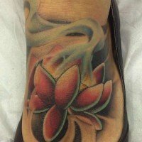 el tatuaje de una flor de loto con humo hecho en color en un pie