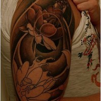 el tatuaje muy bonito de unas flores de loto en olas hecho en el hombro