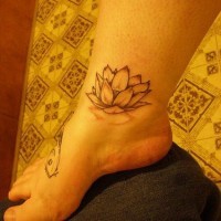 el tatuaje sencillo de una flor de loto en color negro en la pierna