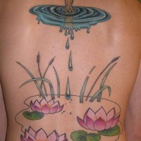 el tatuaje de unas flores de loto enel agua y un arbol hecho en la espalda