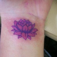 el tatuaje pequeño de una flor de loto de color morado en la muñeca de la mano