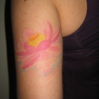 el tatuaje  femenino de una flor de loto de color rosa muy palido hecho en el brazo