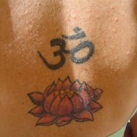 el tatuaje de una flor de loto con el simbolo de mantra om hecho en la espalda