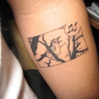 el tatuaje de un pajaro cantando en un arbol hecho con tinta negra