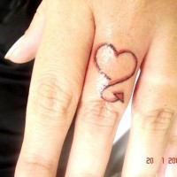 el tatuaje minimalista de un corazon pequeño en color negro con rojo hecho en el dedo