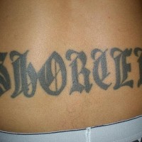Lower back tattoo, big styled letters, black inscription