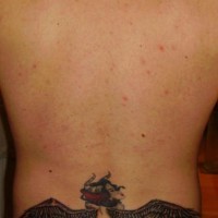 Tatuaje en bajo de la espalda en color diablo mujer con alas negras