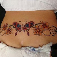 el tatuaje de una traceria colorada con una mariposa en el centro y orquideas a los lados