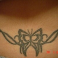 Lower back tattoo, black styled butterfly in curled stripes