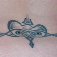 Tattoo mit gesichtsartigem Zeichen am Becken