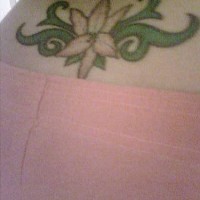 Lower back tattoo, white flower, decorated, green leaves