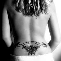 Lower back tattoo, wide text waving and styled skull