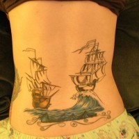 Lower back tattoo, two ships are swimming on waves