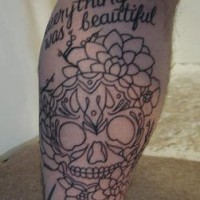 el tatuaje lineado de una calavera mexicana rodeada de flores y un texto