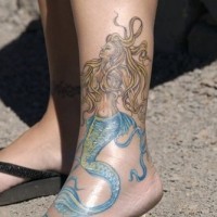 Tatuaggio bellissimo sulla gamba la sirena con la coda azzurra