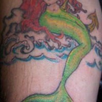 Sirène aux cheveux rouge avec le tatouage brassard de mer