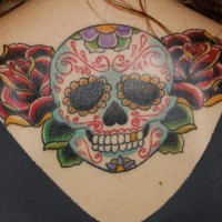 el tatuaje de una calavera mexicana con rosas hecho en la espalda con tinta de varios colores