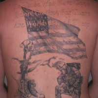 el tatuaje conmemorativo patriotico con un soldado y la bandera americana hecho a toda la espalda