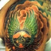 el tatuaje surrealista de una esfera con alas y nubes en el fondo hecho en el hombro