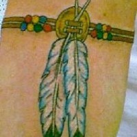 el tatuaje de un talisman en forma de brazalete con dos plumas indianas
