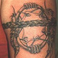 el tatuaje de una trenza en forma de brazalete con un atrapasueños hecho con tinta negra