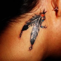 el tatuaje pequeño de dos plumas indianas hecho detras de la oreja