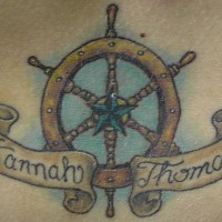 el tatuaje de una rueda del timon con una estrella nautica en el centro con un nombre