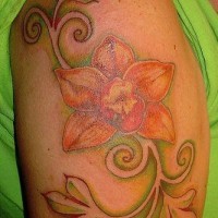 el tatuaje de una orquidea con sus hojas en forma de tracria hecho en el hombro