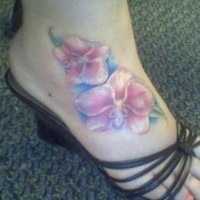 el tatuaje femenino de pie con dos orquideas de color rosa con blanco