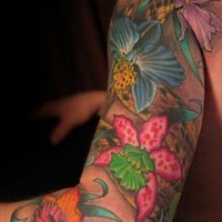 el tatuaje muy colorado a todo el brazo con muchas orquideas de diferentes colores