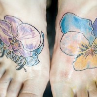 el tatuaje de dos orquideas coloradas hecho cada uno en un pie