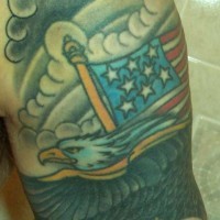 el tatuaje de una aguila volando con la bandera americana sobre el cielo gris