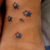 el tatuaje pequeño de unas estrellas con su sombra azulhecho en el pie