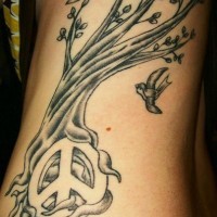 Tatuaje árbol y pa´jaros volando con el signo de la paz