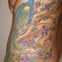 Muy bonito tatuaje en color el pavo real y el árbol en flor