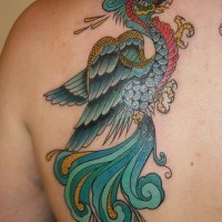 Colourful magic bird tattoo on shoulder blade