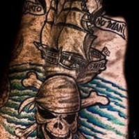 el tatuaje estilo pirata con una calavera y un barco en el mar