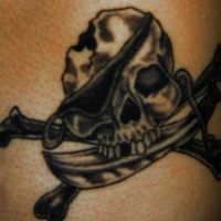 el tatuaje de tinta negra con una calavera pirata con cuchillo en su boca y los huesos cruzados