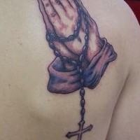 el tatuaje en la espalda de las manos orantes con rosario