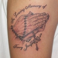 Praying hands with rosary tattoo on arm
