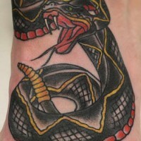Un serpent à sonnette noir avec le tatouage sur le pied