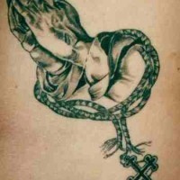 el tatuaje realista de tinta negra con manos orantes y un rosario